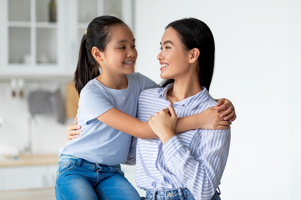 A mother and daughter, who look alike, hugging each other.